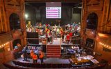The historic Citizens Theatre stage is busy with people browsing stalls of theatrical props, costumes and posters. There are lots of red and yellow balloons throughout the space.