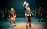 Production image. Several figures in scruffy 1950s style clothing stand on stage.