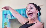 A woman makes an animated facial expression and points.