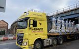 Six statues securely fastened to the back of a large lorry.