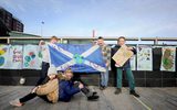 Five young children are standing outside and holding a scottish flag. The flag has 'keep the world cool' painted on it.