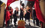 An outdoor performance, Three women dressed as witches standing around a prop cauldron.