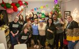 The group of participants at the Elder Street 2023 Christmas sharing pose with Citizens Theatre staff. Christmas decorations can be seen in the background.