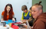 A group of women are sitting round a table looking at magazines