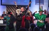 A festive performance. A group of actors dressed as the baddies from different fairytales. There are musicians behind them.