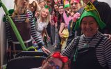 A group of people wearing colourful costumes and holding theatrical props. They are smiling at the camera.