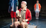 A production shot. Three men in colourful sorts attire stare into the distance.