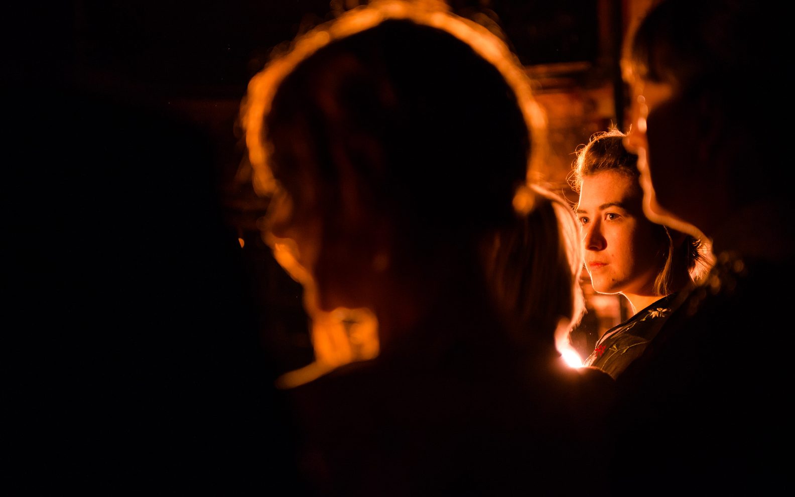 Backstage at a theatre show. A young woman is standing in the wings and a spotlight is shining on them.
