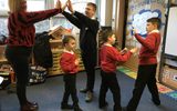 A classroom. Four young boys are playing with a teacher.