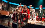 A very theatrical production image of a group of young people in colourful punk clothing.