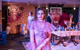 A highly theatrical production Image of a theatre show. A woman with a pink ball gown and smeared make up looks into the camera.