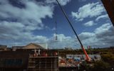 A wide shot of a statue being lowered onto the Citizens Theatre roof via a crane. The statue is hovering above the building.