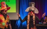 Two men dressed as clowns standing on a stage.