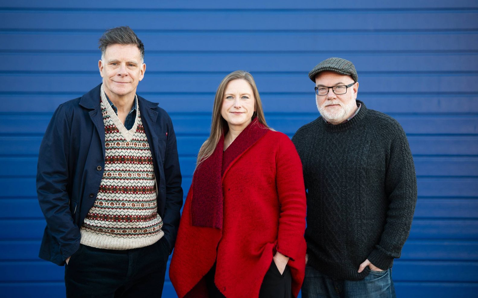 Ricky Ross, Frances Poet and Dominic Hill standing in front of a blue shutter looking directly at the camera.