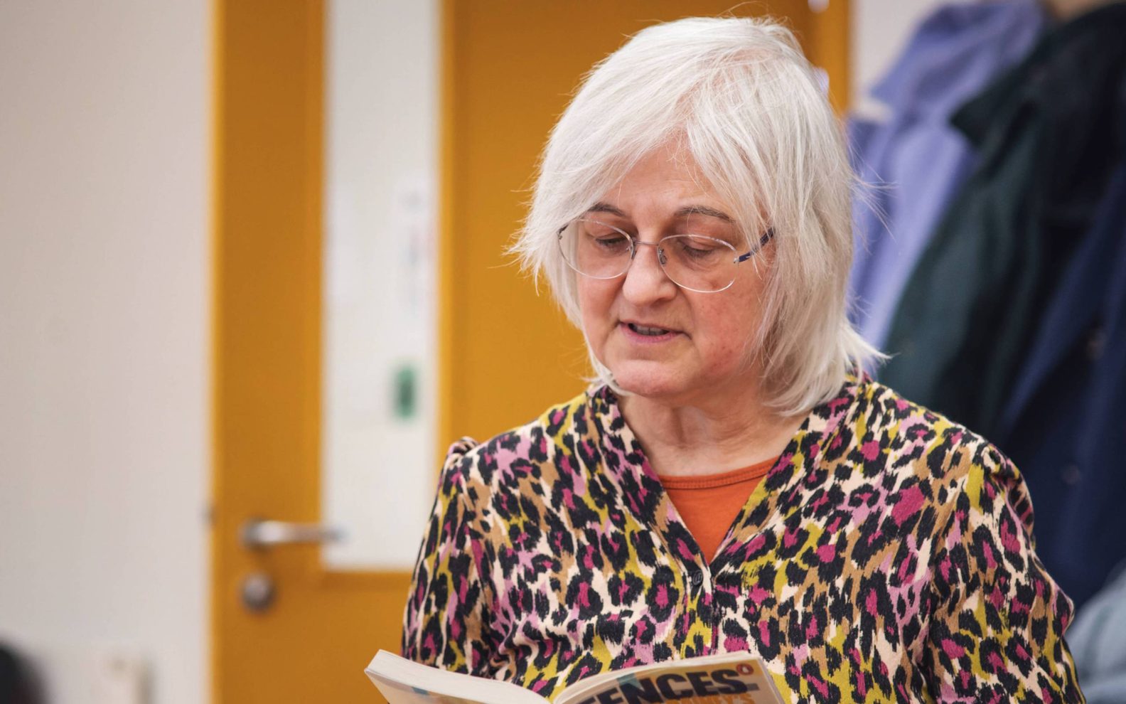 A play reading session. A woman reads from a copy of the play 