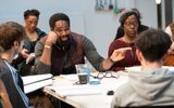 A group in a a rehearsal room around a table.