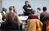 A group in a a rehearsal room around a table.