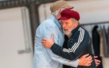Two men dressed casually are hugging each other.