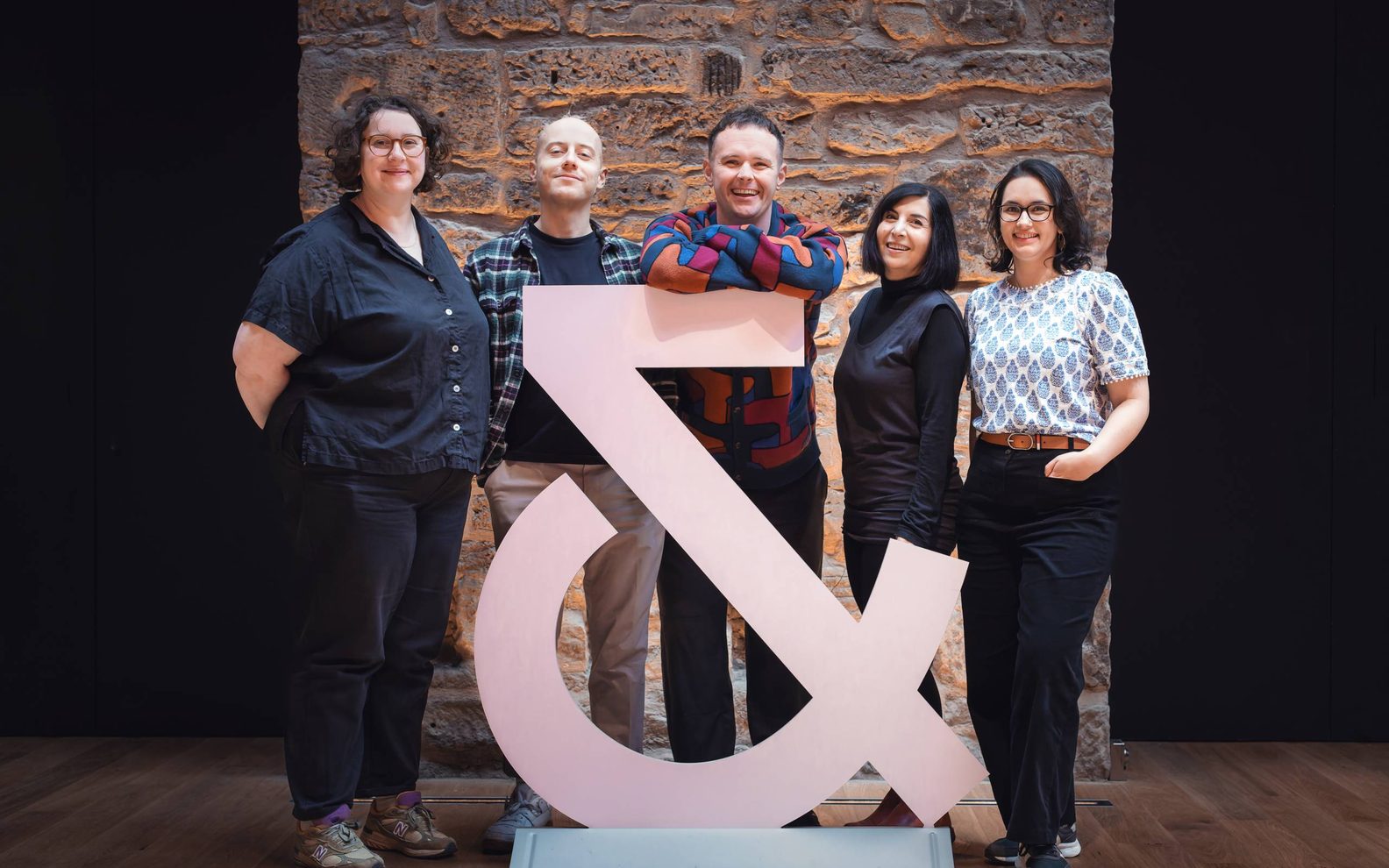 Group of associate artists standing behind of our ampersand