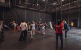 A group of adults and children dancing with headphones on in a studio space. Some are waving colourful flags.