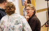 Two people laughing and chatting in a rehearsal room.