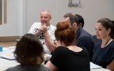 Actors reading scrops around a table.