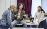 Rehearsals for East is East. Zaki Ali sitting on a table, gesturing with his hands.