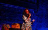 A performer singing into a microphone on stage
