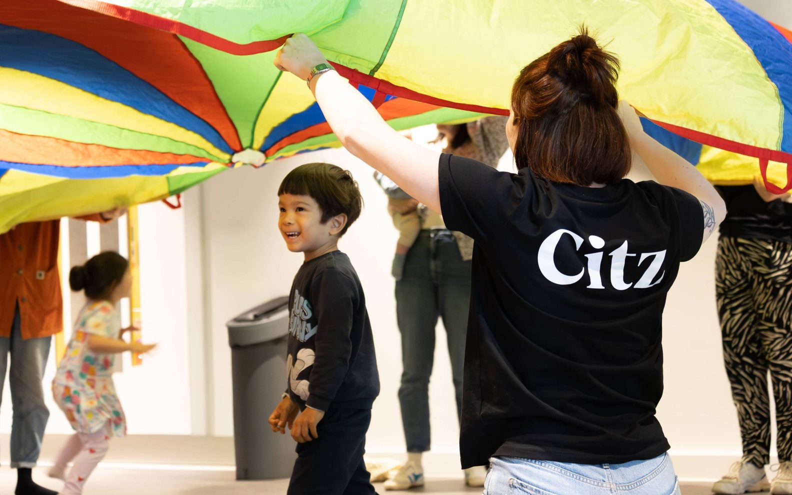 Young kid under a rainbow coloured parachute
