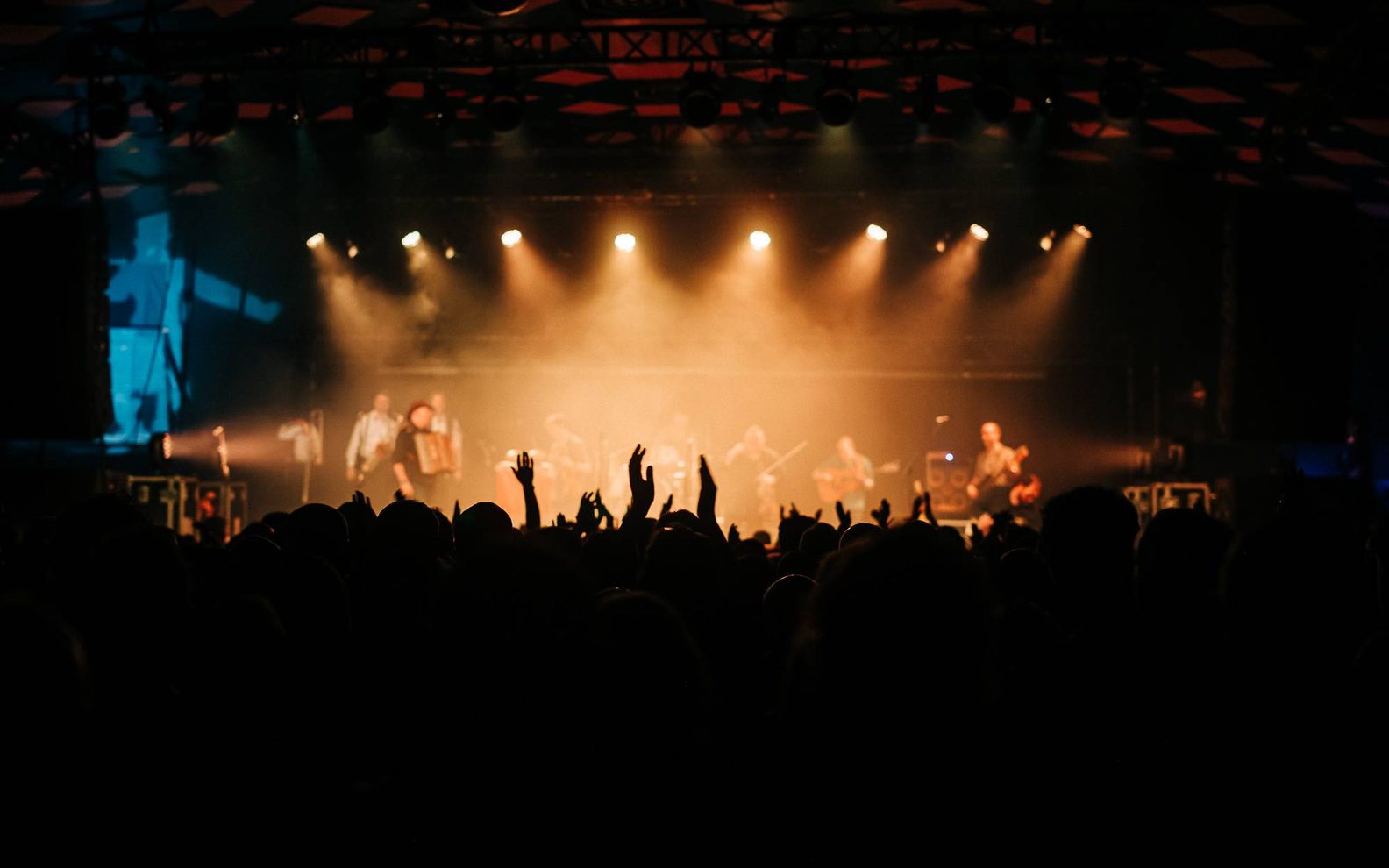 a busy crowd and out of focus stage with a band